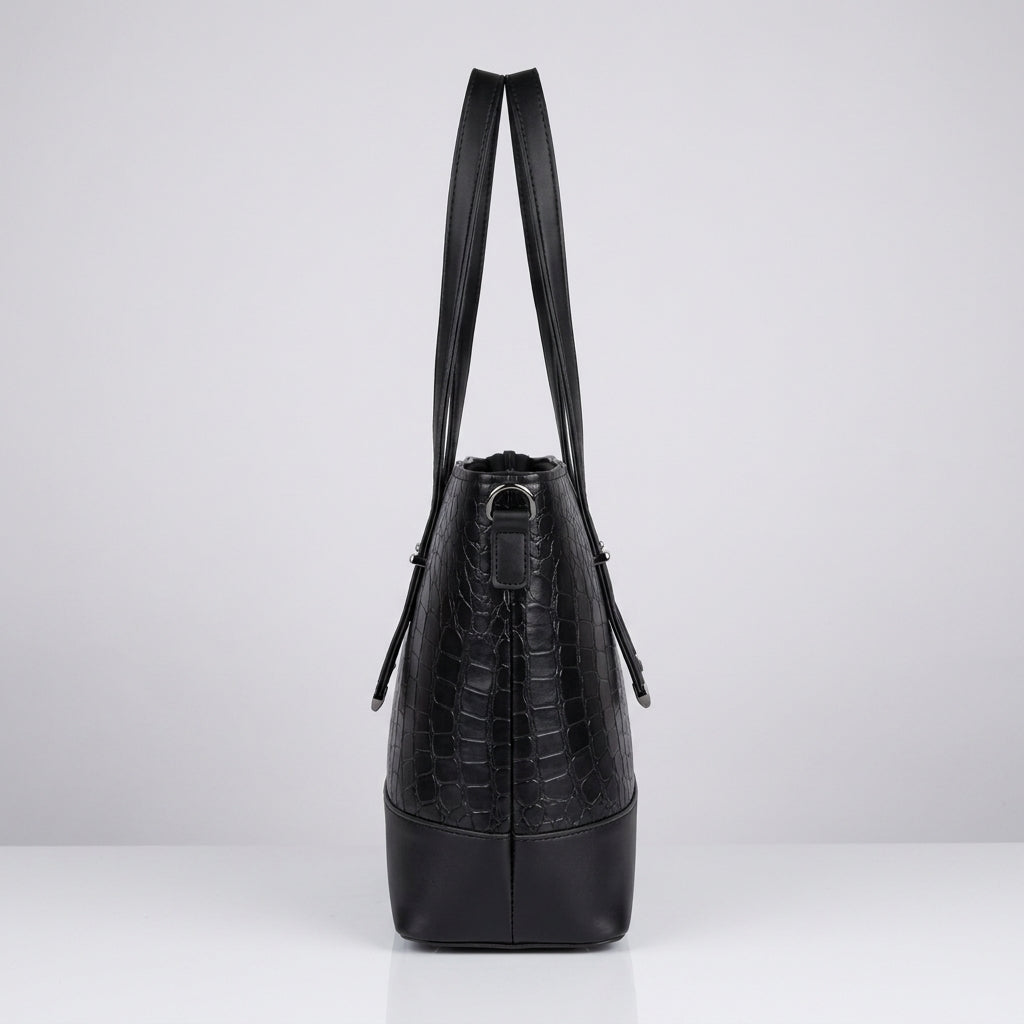 A black crocodile-embossed leather shoulder bag with a structured cylindrical shape, shown from the back against a light gray studio background.
