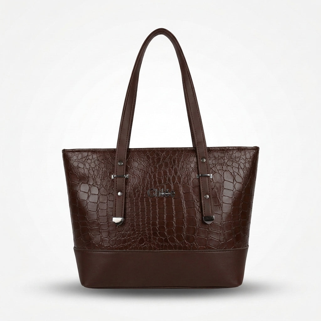 A dark brown tote bag with an embossed crocodile pattern, featuring dual shoulder straps, silver-tone hardware, and a small metallic logo plaque on the front, set against a clean white background.